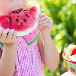 child eating a large piece of watermelon