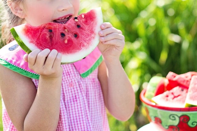 child eating a large piece of watermelon