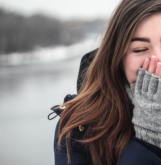 Woman Sneezing into Hand While Outside