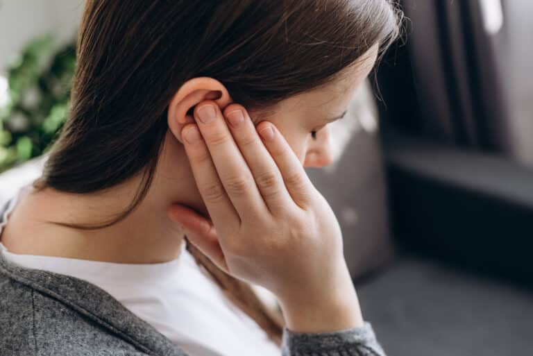 Woman with ear infection holds ear