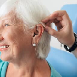 Senior woman smiling as she gets her first hearing aid