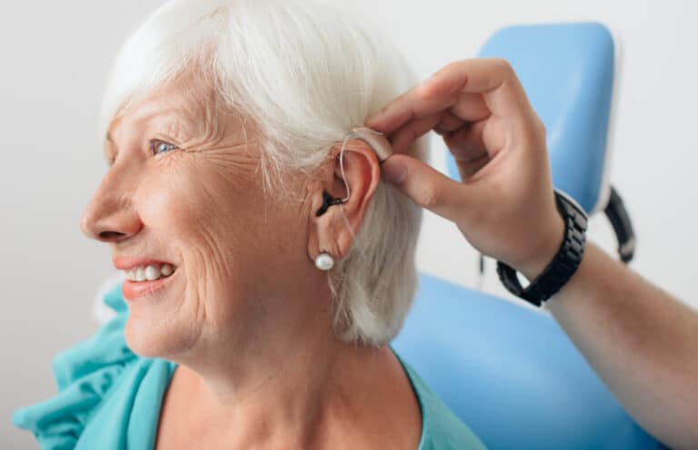 Senior woman smiling as she gets her first hearing aid